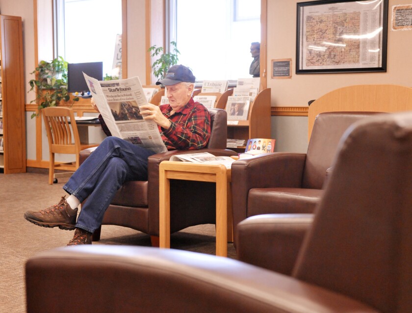 man reading newspaper in library