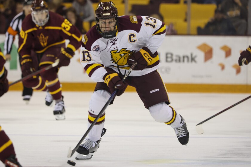 A college hockey player plays in an indoor rink
