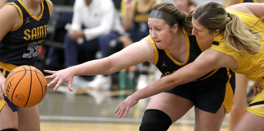 St. Scholastica’s Liz Frase (4) reaches for a loose ball with UW-Superior’s Sam Parendo (11)