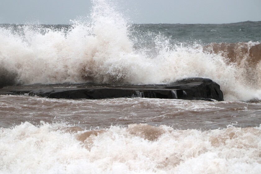 Waves crash over rocks.