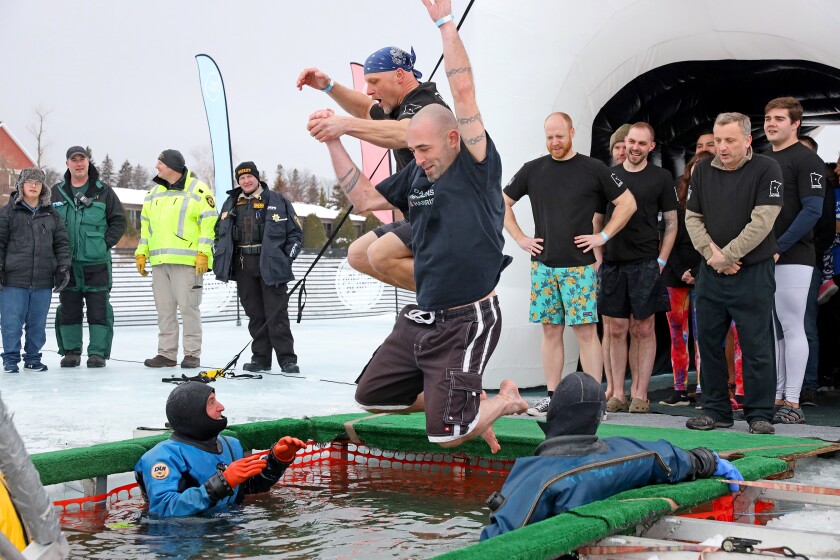 People jump into the water during the Polar Plunge event on Pelican Lake.