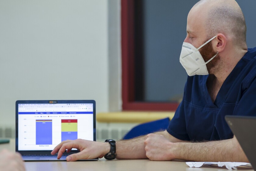 People at a meeting table with laptops and face masks