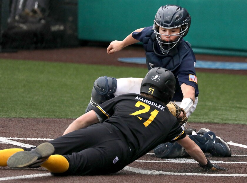 Hermantown catcher River Freeman (12) flags down Duluth Marshall's Owen Marsolek (21) on home plate