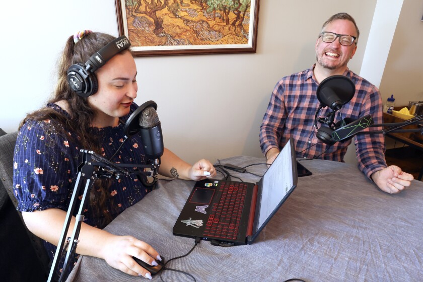Man laughing while woman reads from a computer.