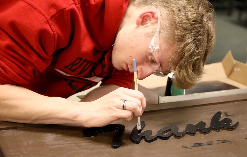 Senior Dawson Kriske does some touch up painting to the Lake Nebagamon sign