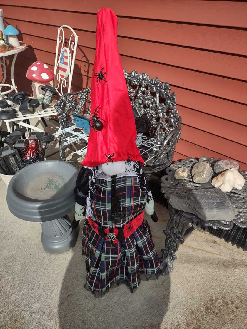 A red and black gnome woman with spiders around her hat and belt.