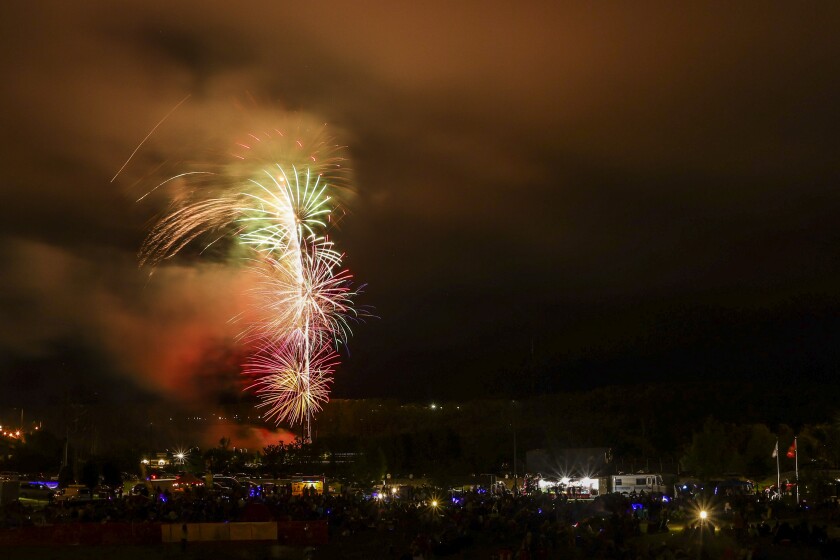 Large aerial fireworks burst in cloudy foggy night sky
