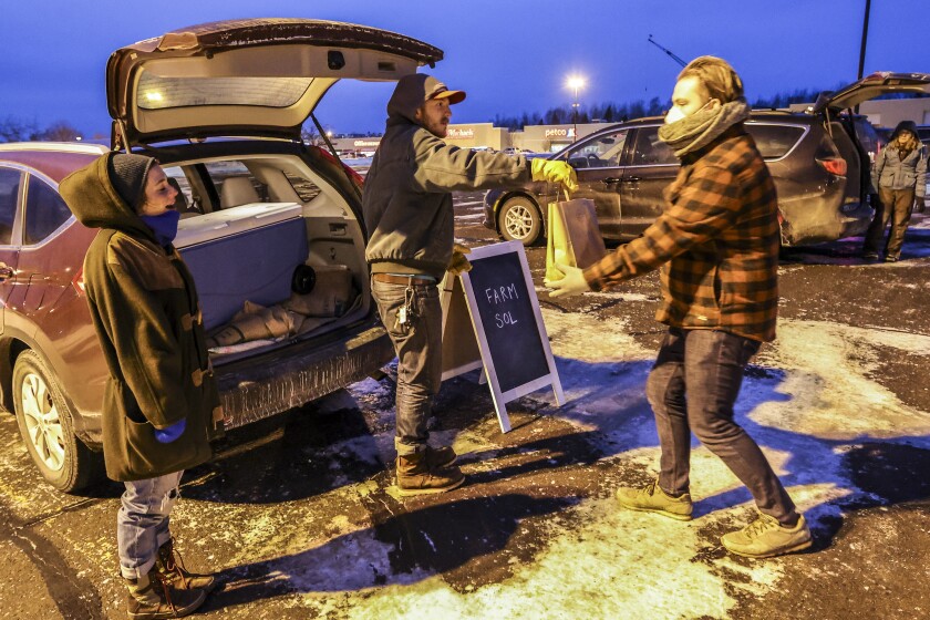 Merchants and customers exchanging goods in parking lot at dusk during the winter months