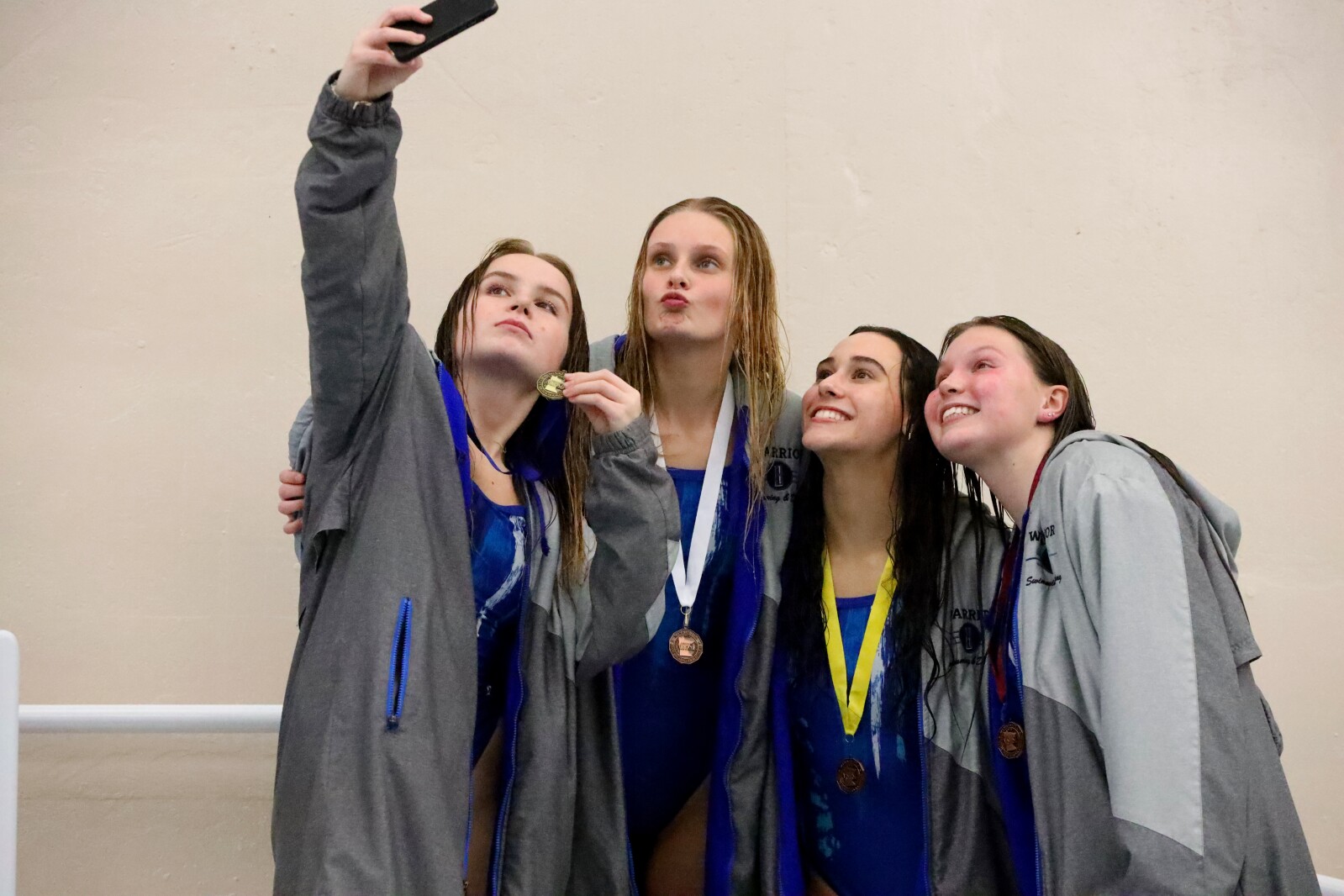 Divers stand on the podium with their medals and take a selfie.