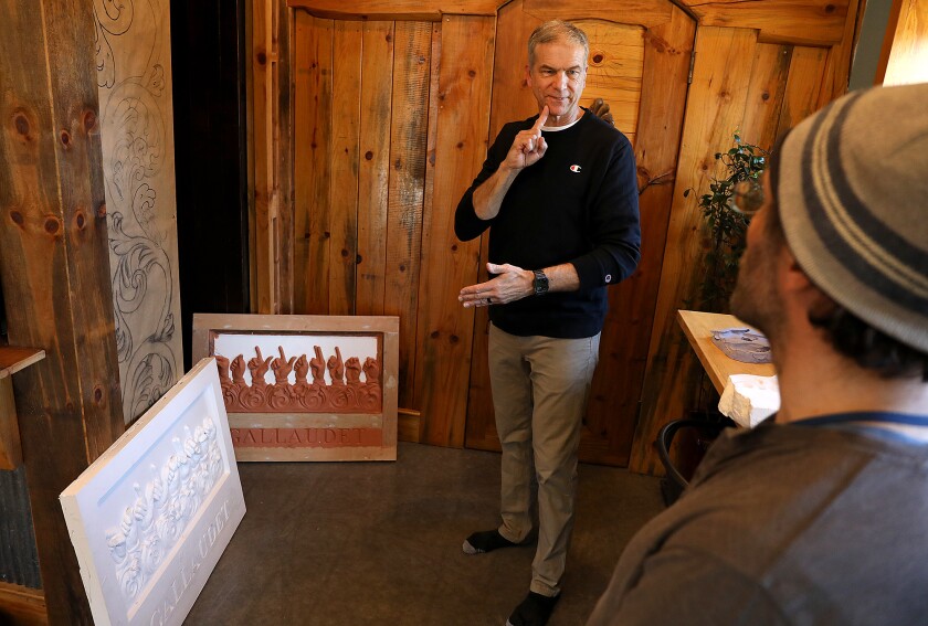 Artist Steven Peterson, left, signs his answer to a question to translator Doug Bowen-Bailey during an interview