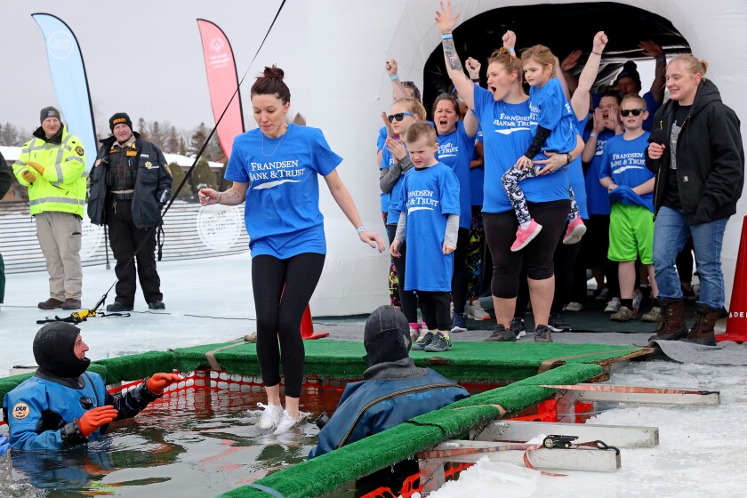People jump into the water during the Polar Plunge event on Pelican Lake.