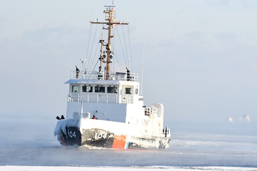 Crew members of the Biscayne Bay toss ice overboard on Lake Superior