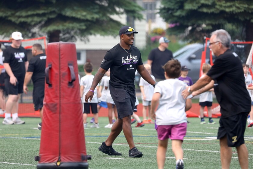 A pro football player walking and smiling during a youth camp.