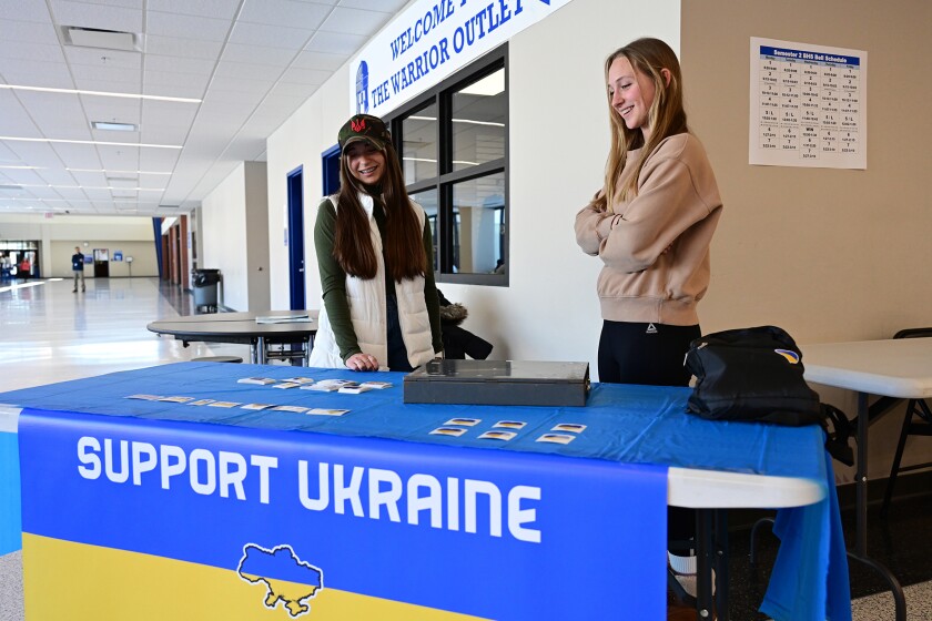 Anastasiia Biemaier and Lila Collins at a table to raise money for Ukraine.