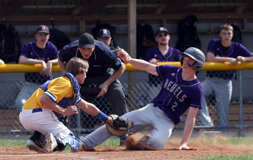 Umpire watches as Adrian/Ellsworth Dragons catcher Kyler Kunkel tags Murray County Central runner Connor DeGreeff (2) as he attempts to score a run Monday evening in Adrian.