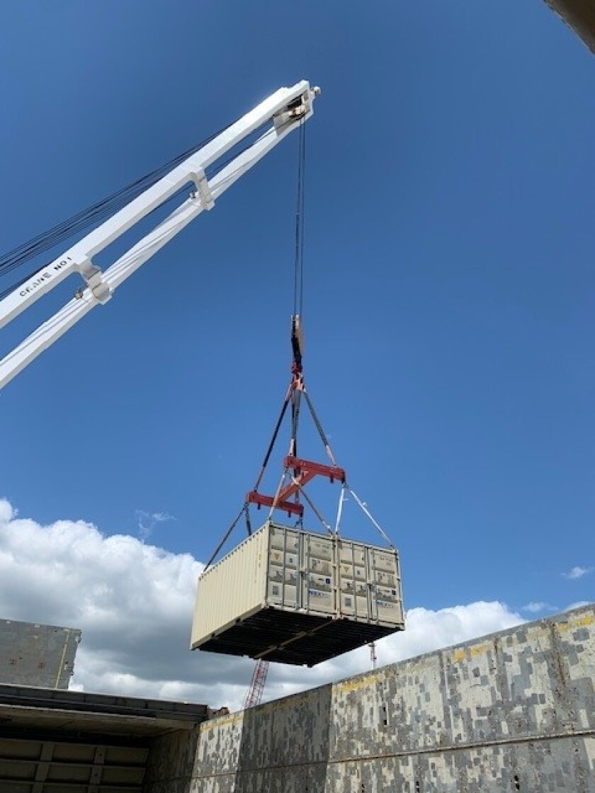 A crane unloads a box from a ship.