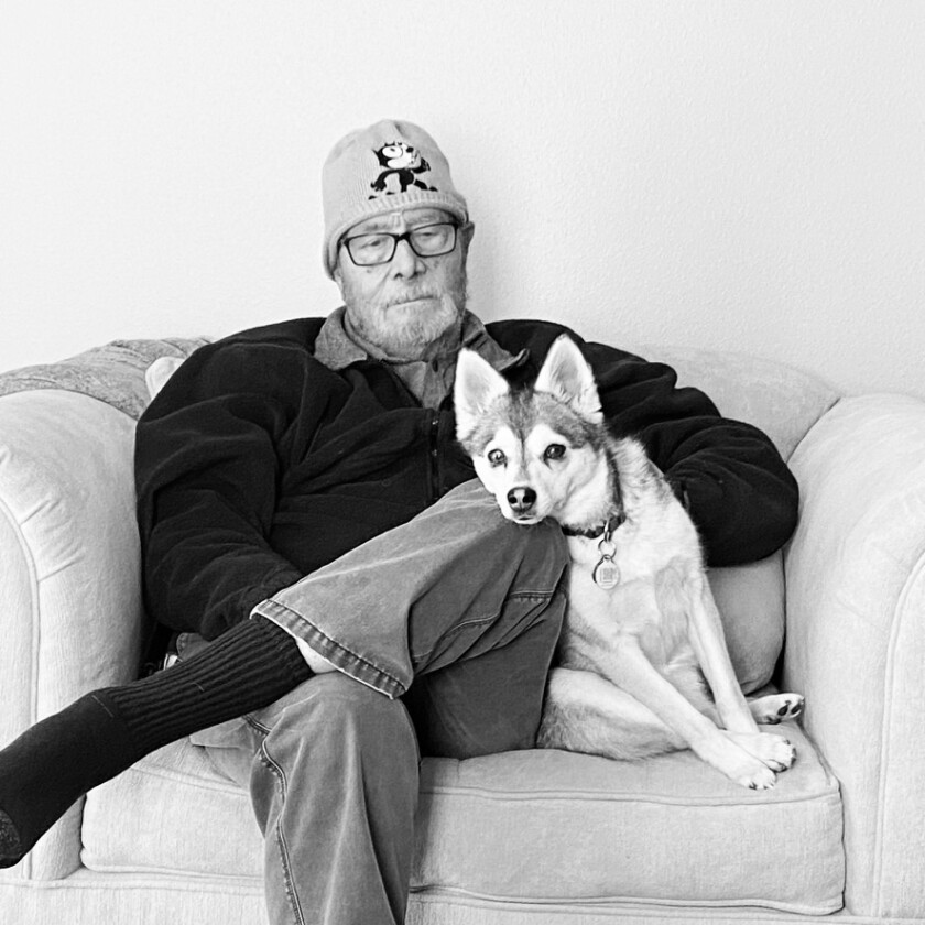 Doug Hamilton solemnly sits in a chair with a dog
