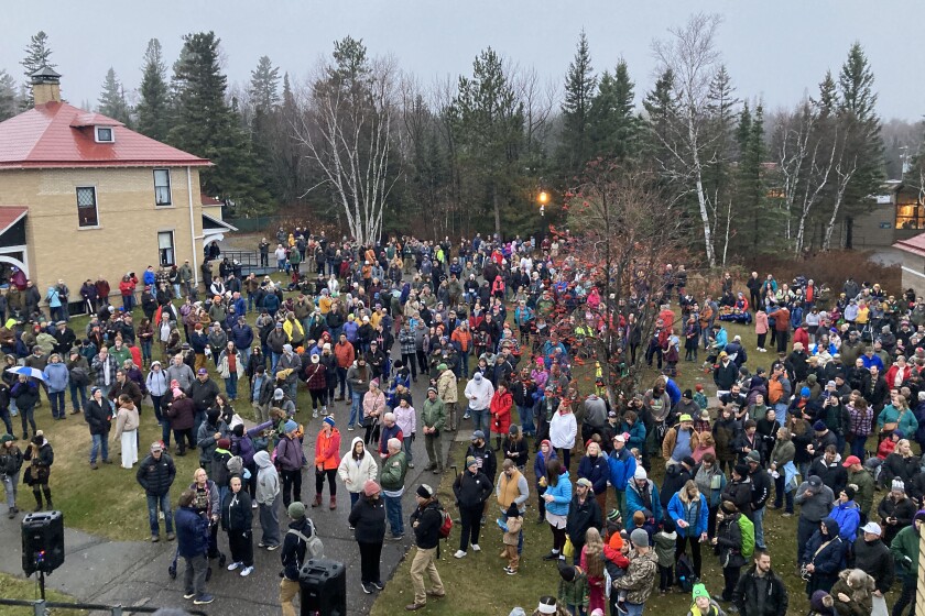 A crowd of people gathered outside of a lighthouse for a ceremony.