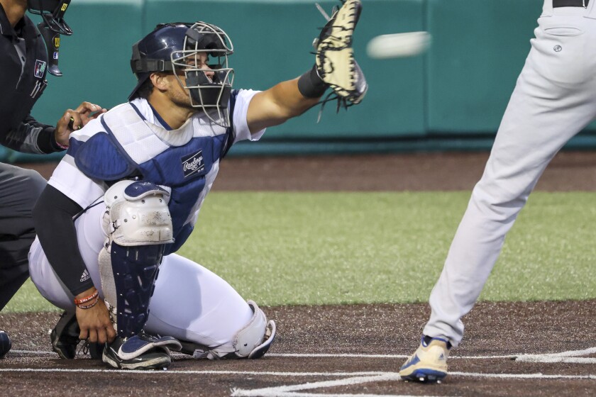 Baseball players in white and blue uniforms playing a game at outdoor stadium