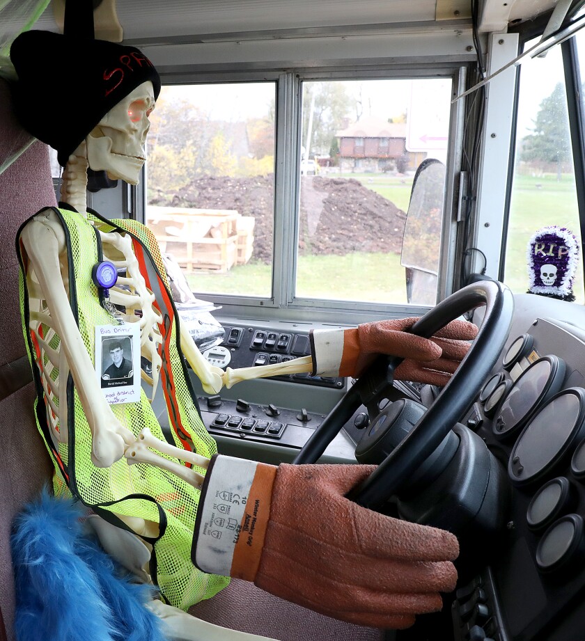 A skeleton is behind the wheel driving the haunted school bus