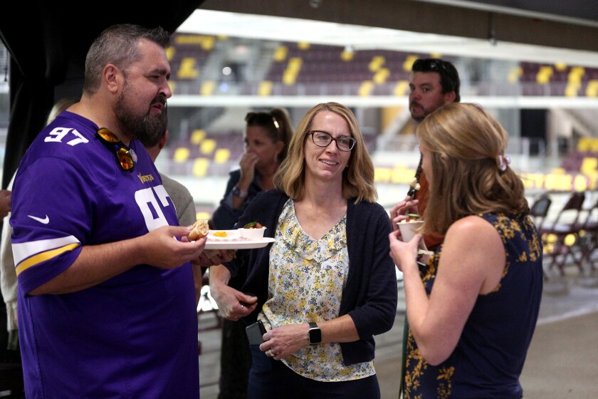 A man and two women chatting while sampling concession food items.