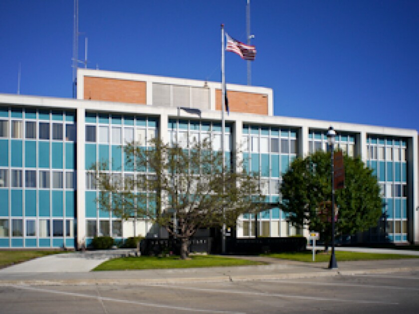 Retro-looking government building with blue and brick facade and US flag flying on pole outside.