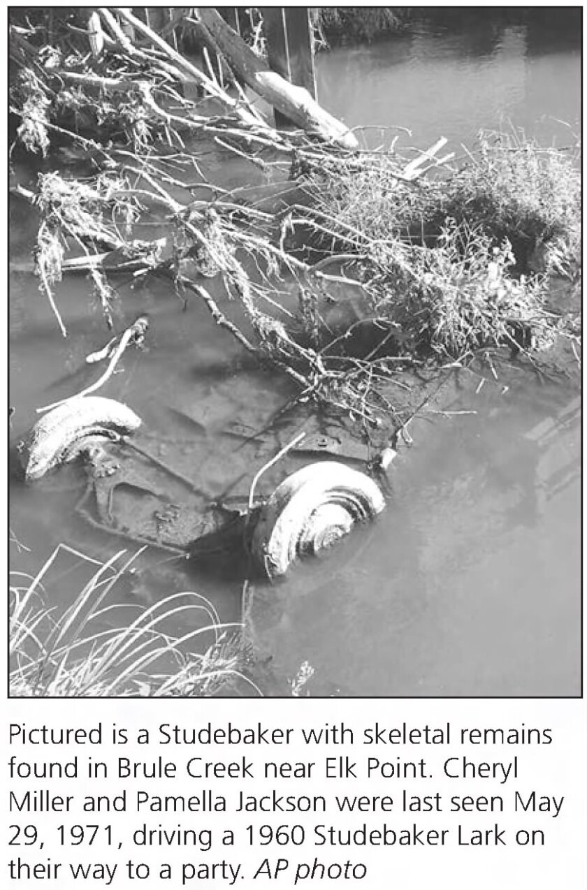 A historical newspaper clipping shows a photo of a body of water with an inverted car with wheels exposed, sticking out of the water.
