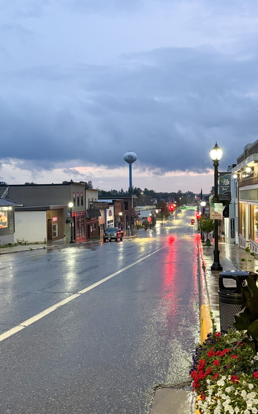 A street going through a small town that is wet during rainfall.