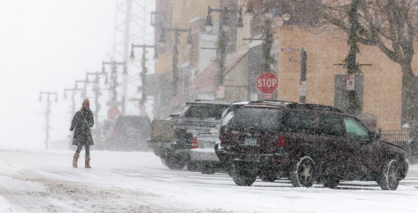 A pedestrian walks across 10th Street to her car Tuesday morning during a period of snowfall in Worthington.