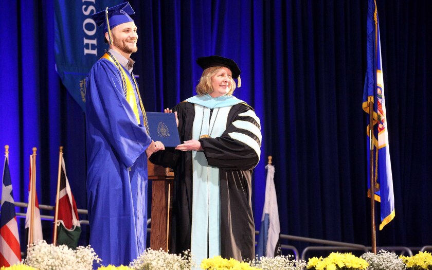 Graduate and college president pose together