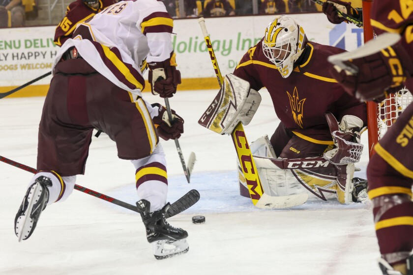 A college hockey player plays in an indoor rink