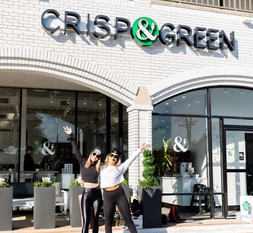 Dos mujeres frente a un restaurante Crisp & Green.