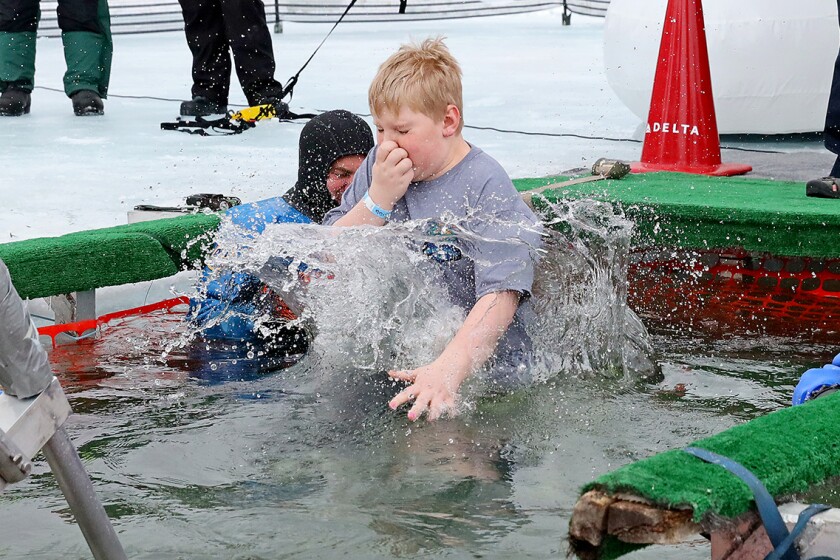 People jump into the water during the Polar Plunge event on Pelican Lake.