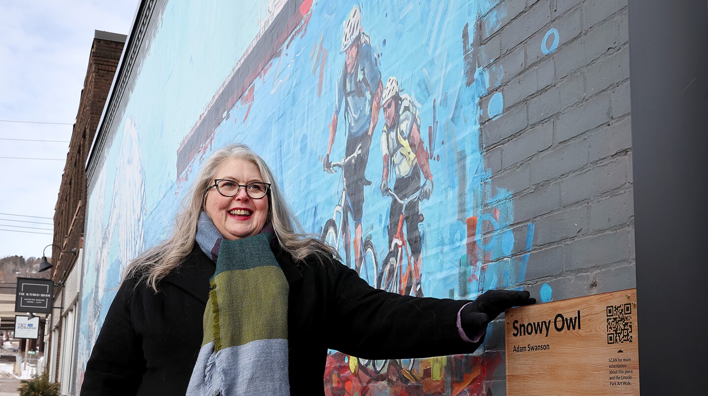 Woman stands by mural.