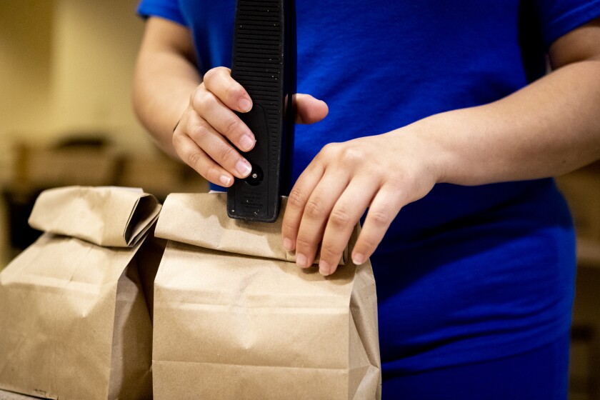West Central Industries kitchen manager Angela Rodriguez staples meals in bags shut before sending them off to be distributed for Meals on Wheels at West Central Industries on Friday, May 20, 2022.