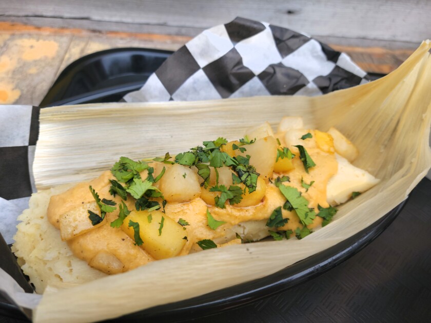 A tamale is covered in amarillo mole, chayote squash, jicama, cilantro and pineapple.