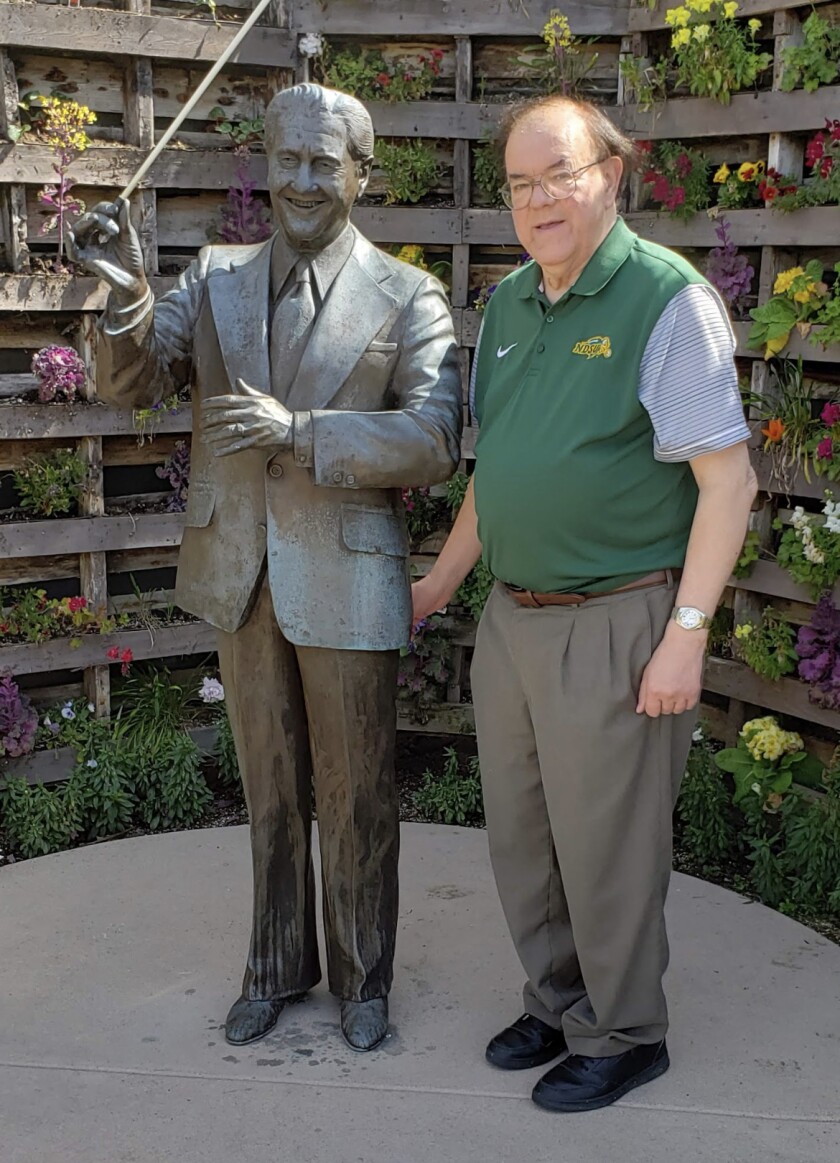 man stands with a statue of Lawrence Welk