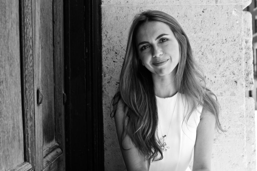 A woman poses in front of a wall. 