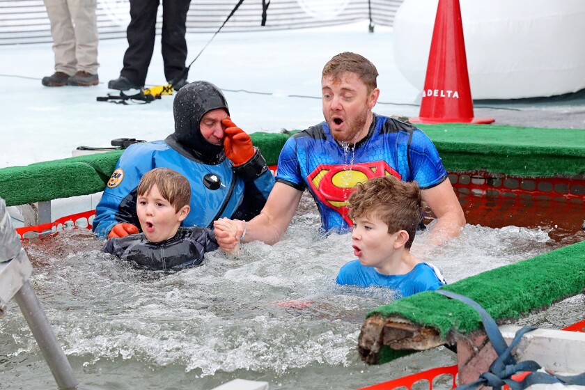 People jump into the water during the Polar Plunge event on Pelican Lake.