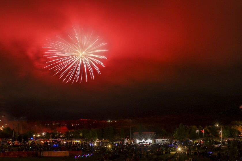 Large aerial fireworks burst in cloudy foggy night sky
