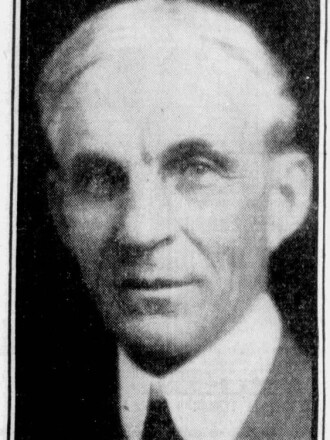 a historical news clipping showing a profile photo of a man in a suit and tie