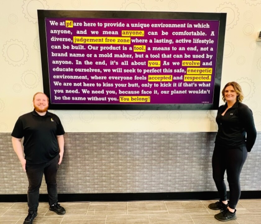 A man and a woman are standing in front of a billboard. 