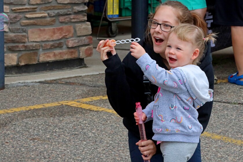 A bubble floats out of frame as a woman and girl watch.