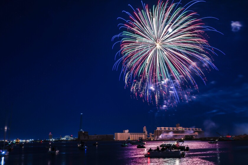Fireworks fill night sky with moon over harbor