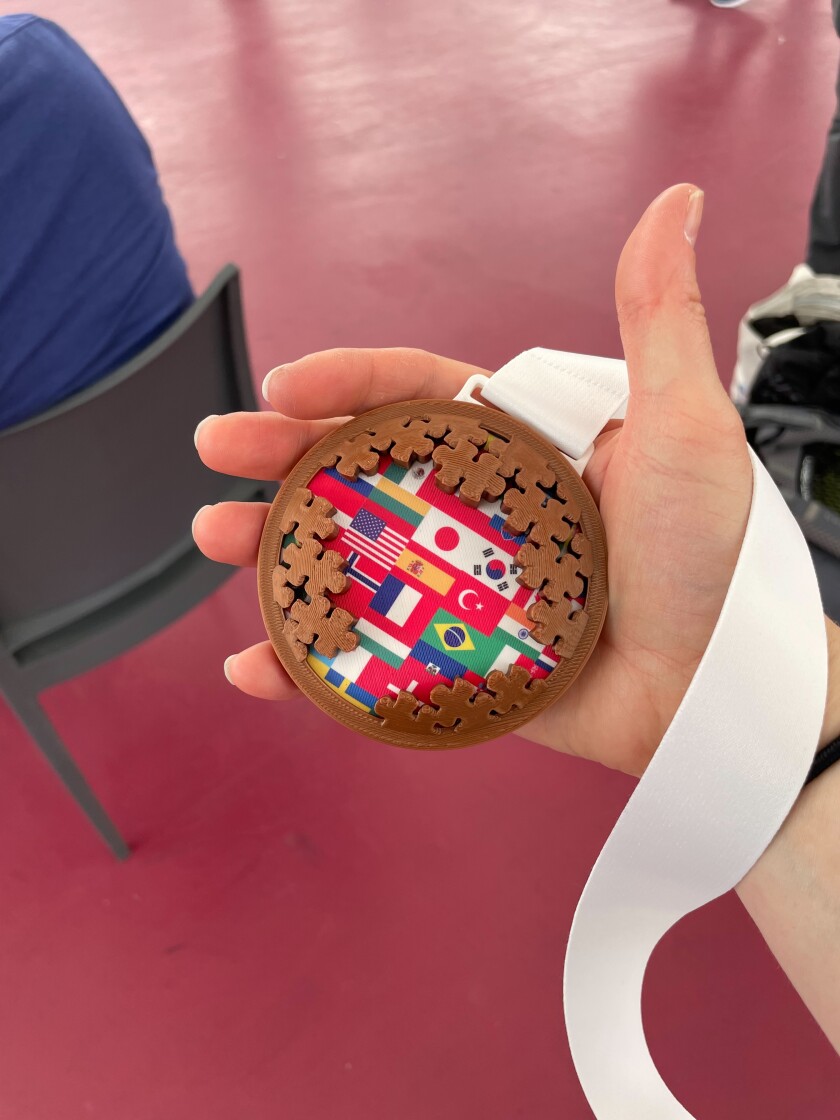 A wooden medal featuring world flags and jigsaw puzzle pieces.