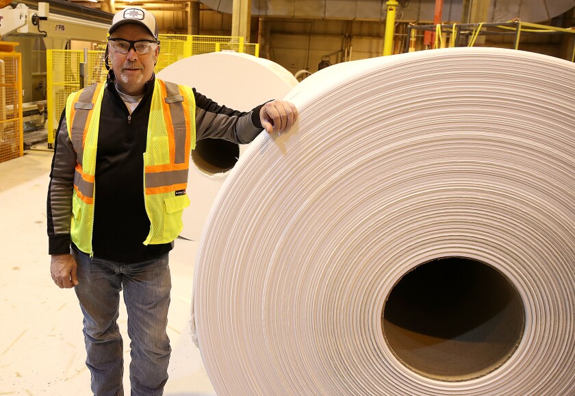 Un uomo si china su un enorme rotolo di carta velina.