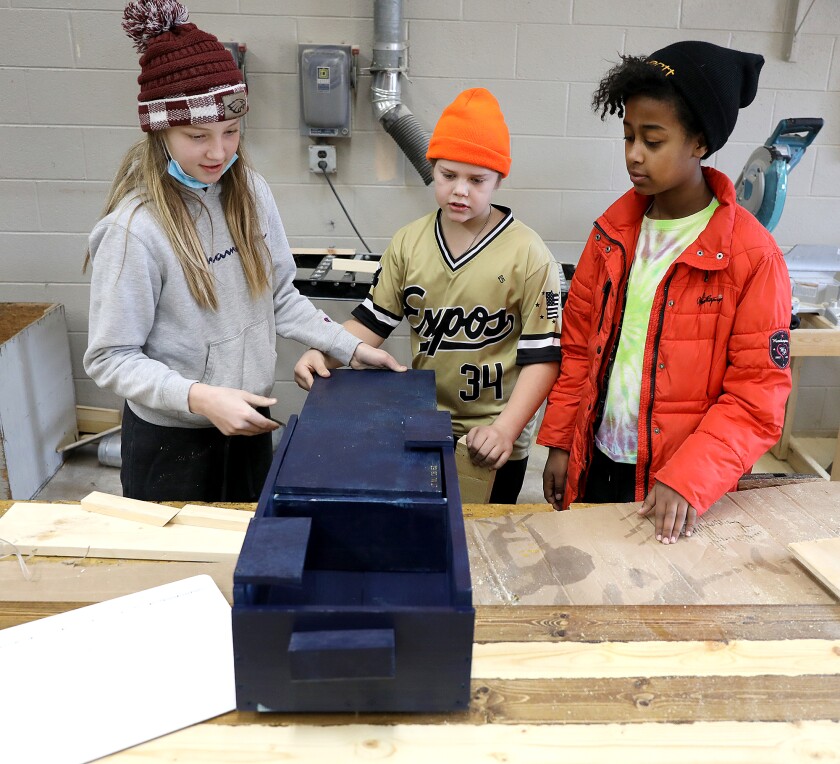Sixth-graders Claire Beerntsen, left, Ezra Ahlberg, center, and Mazzy Johnson explain their portable fire kit