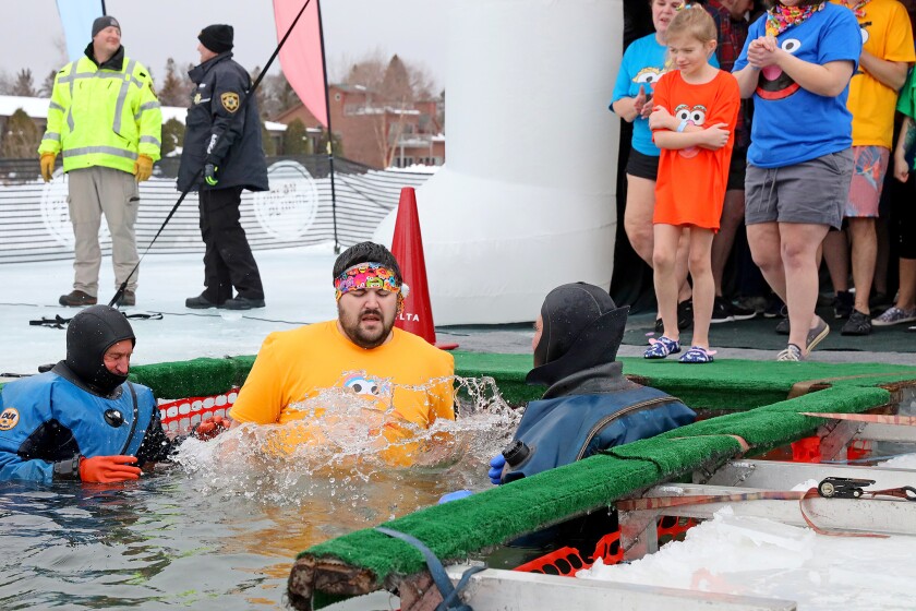 People jump into the water during the Polar Plunge event on Pelican Lake.