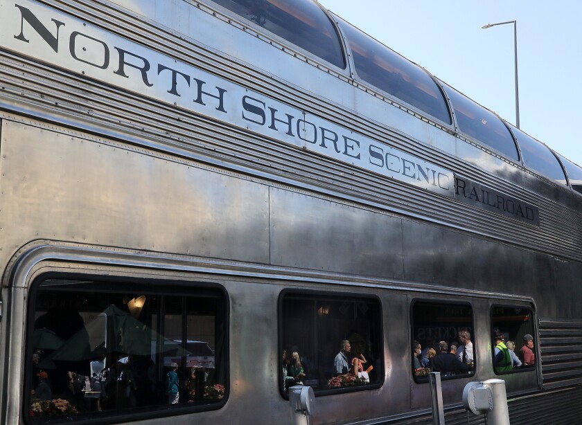 Cruise ship passengers are reflected as they wait to board the North Shore Scenic Railroad