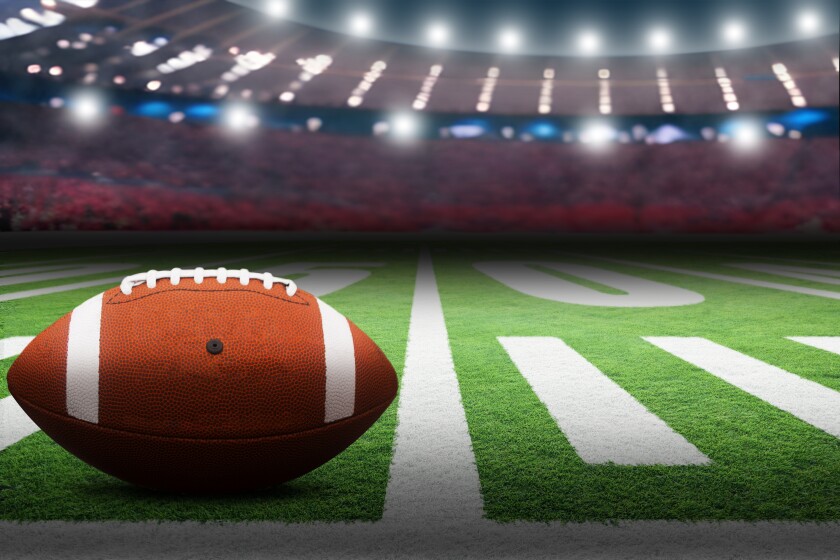 American football on field with dramatic spot lights on ball